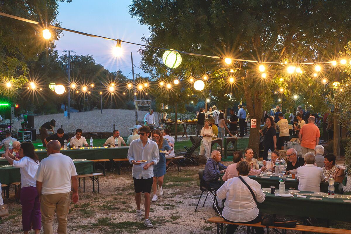 Le tavolate sotto le luci, con la festa che continua fino a tardi