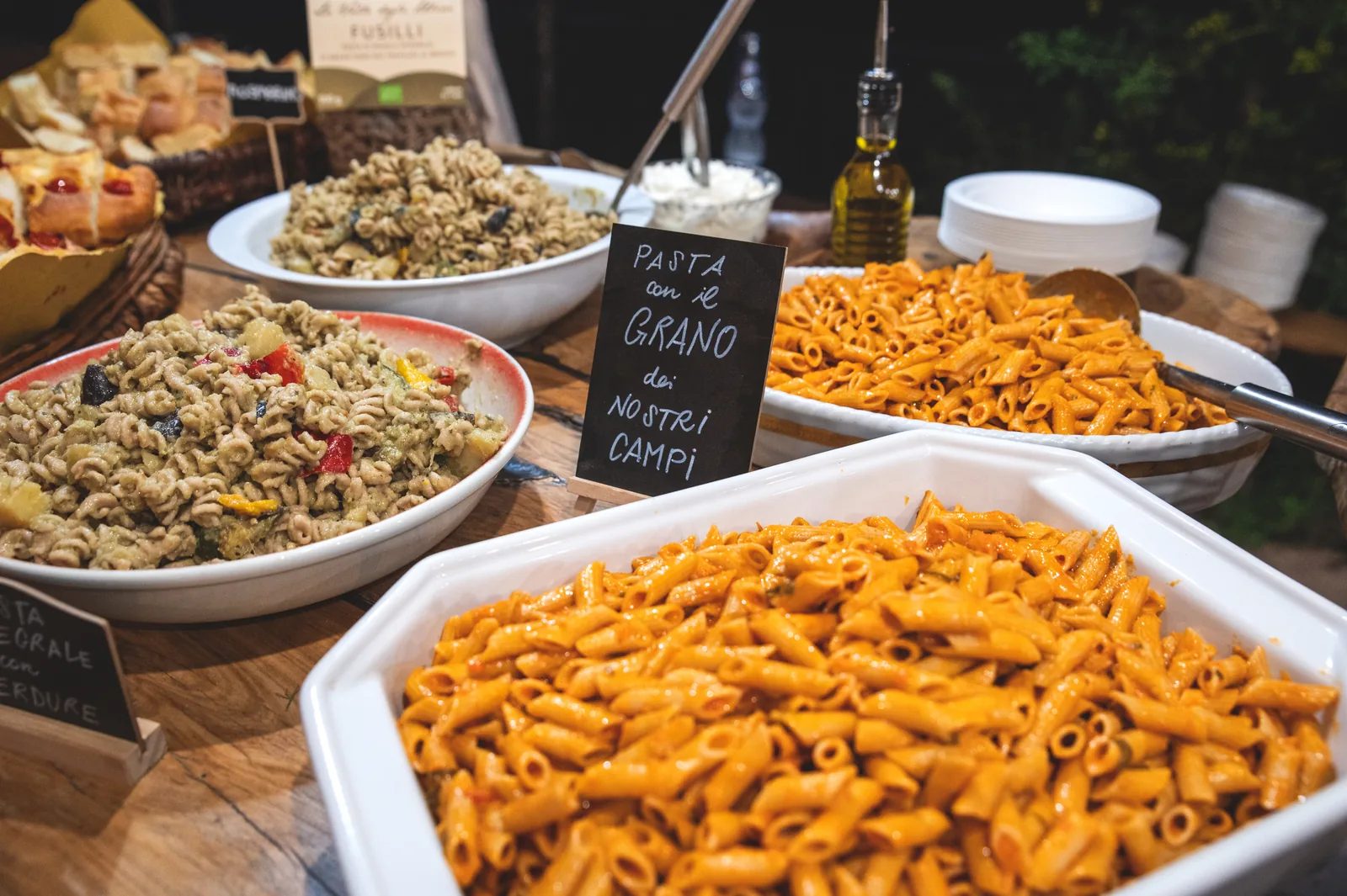 Buffet di una festa con la pasta del grano dei nostri campi, servita in vassoi accanto al cartello scritto a mano