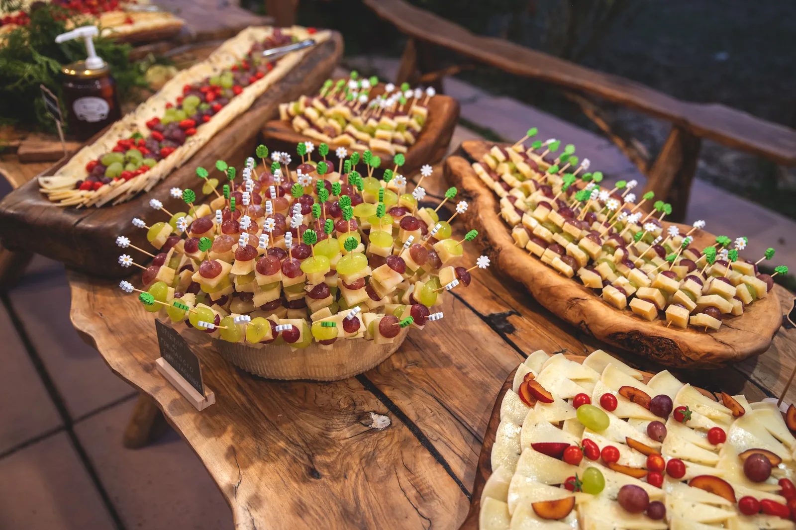 Taglieri di legno con spiedini di formaggio e frutta, pronti per il buffet della festa
