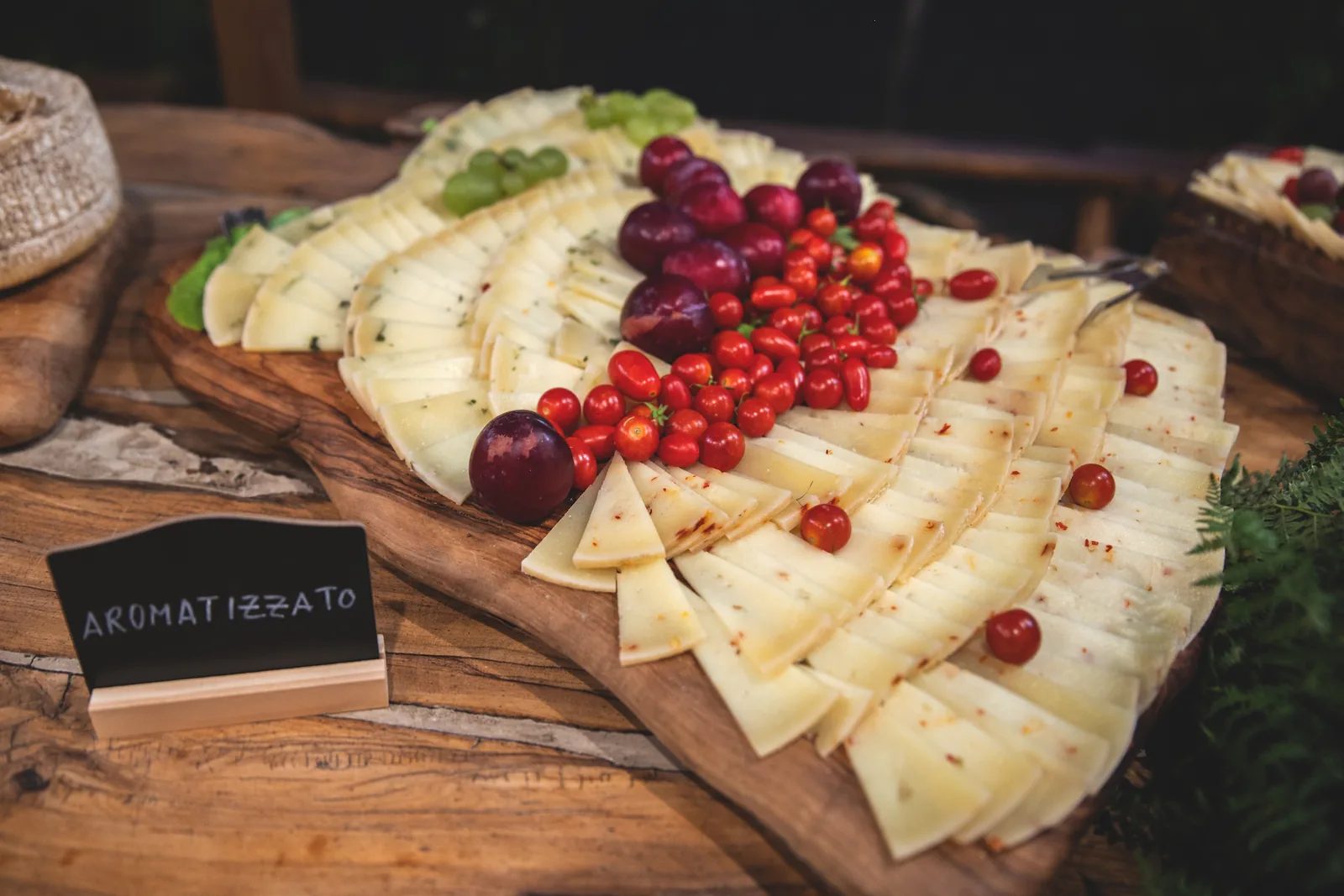 Pecorino aromatizzato a fette con uva e pomodorini, servito sul tagliere